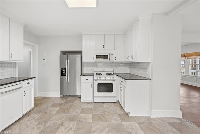 kitchen with white appliances, white cabinetry, baseboards, tasteful backsplash, and dark countertops