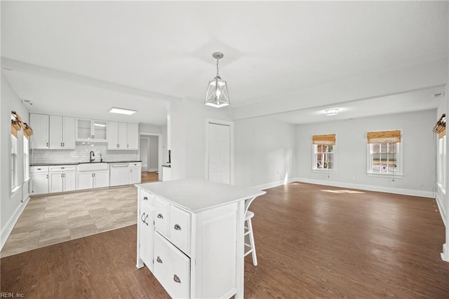 kitchen with baseboards, wood finished floors, decorative light fixtures, white cabinetry, and backsplash