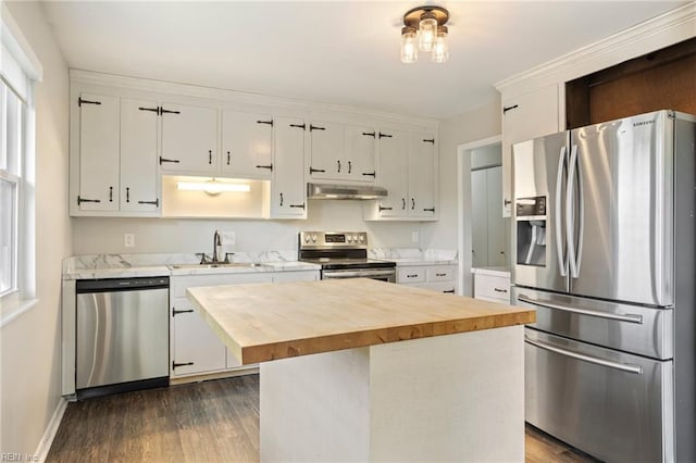 kitchen with stainless steel appliances, a kitchen island, wood counters, and white cabinets