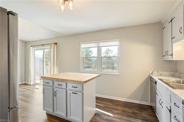 kitchen featuring dark wood-type flooring, butcher block countertops, a sink, white cabinets, and appliances with stainless steel finishes