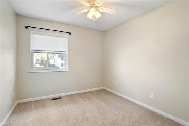 empty room featuring light carpet, ceiling fan, visible vents, and baseboards