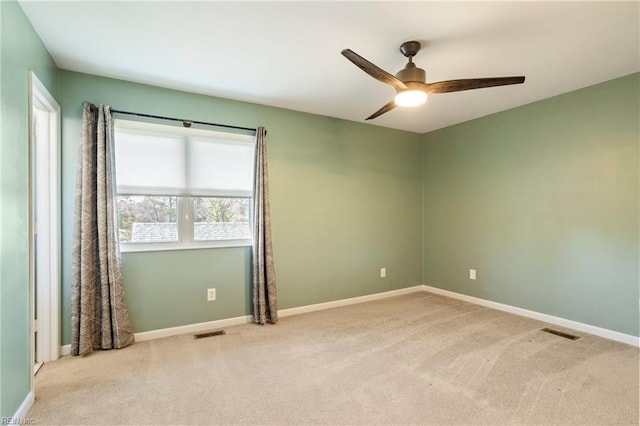 spare room featuring light colored carpet, visible vents, and baseboards