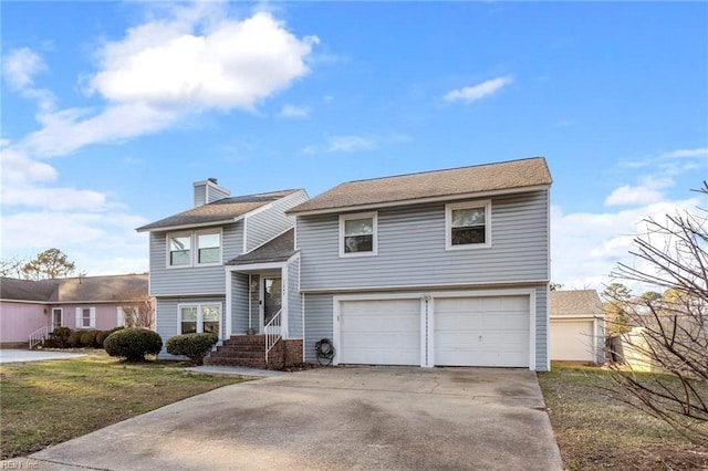 bi-level home with a garage, a front yard, concrete driveway, and a chimney