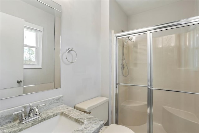 bathroom with vanity, a shower stall, and toilet