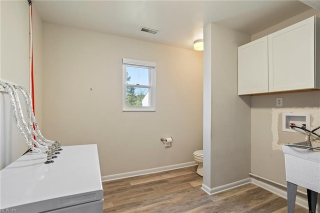 washroom featuring baseboards, wood finished floors, visible vents, and hookup for a washing machine