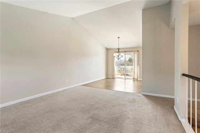 empty room with carpet, vaulted ceiling, baseboards, and an inviting chandelier