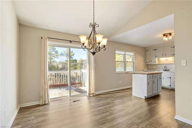 kitchen featuring baseboards, light countertops, a center island, dark wood finished floors, and decorative light fixtures