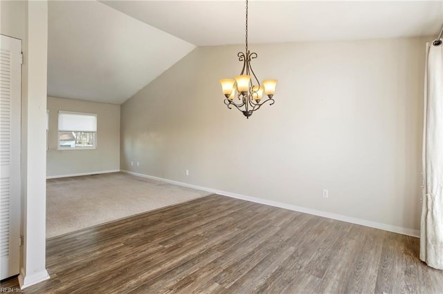 spare room featuring baseboards, vaulted ceiling, a notable chandelier, and wood finished floors