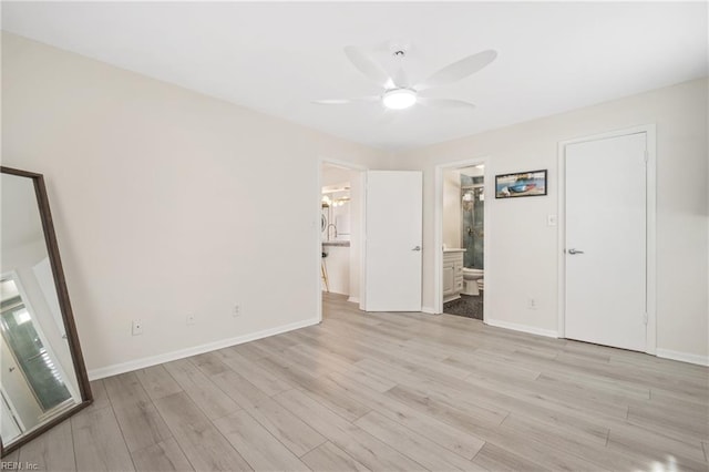 unfurnished bedroom with ceiling fan, light wood-style flooring, baseboards, and ensuite bathroom