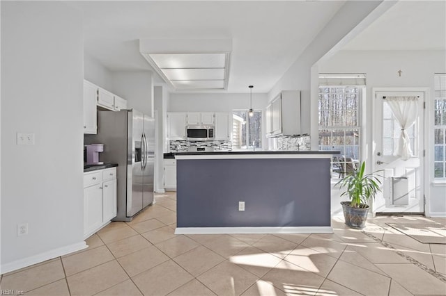 kitchen with tasteful backsplash, dark countertops, stainless steel appliances, white cabinetry, and light tile patterned flooring