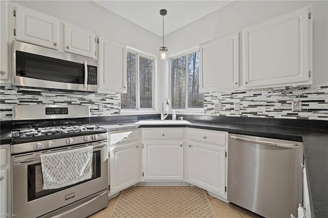 kitchen with appliances with stainless steel finishes, white cabinetry, a sink, and tasteful backsplash