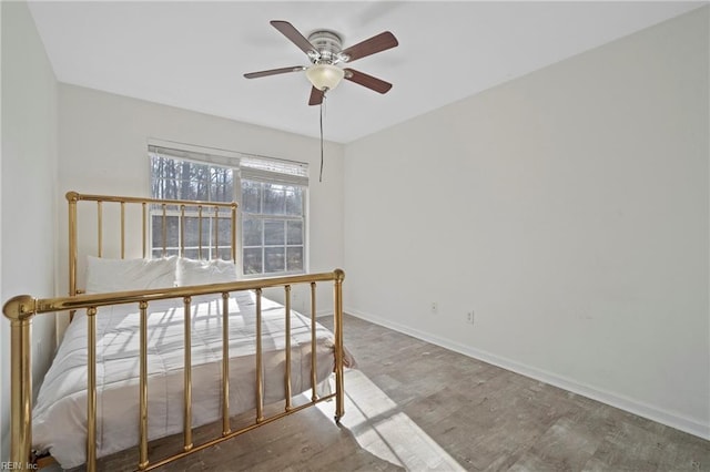 unfurnished bedroom with wood finished floors, a ceiling fan, and baseboards