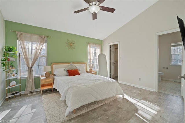 bedroom with ceiling fan, baseboards, vaulted ceiling, a spacious closet, and ensuite bath