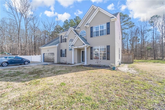 traditional-style home with an attached garage, driveway, fence, and a front lawn