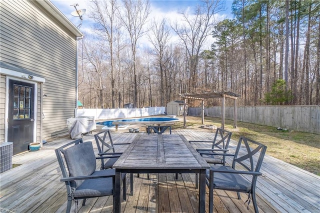 deck with a fenced in pool, a fenced backyard, an outbuilding, outdoor dining area, and a shed