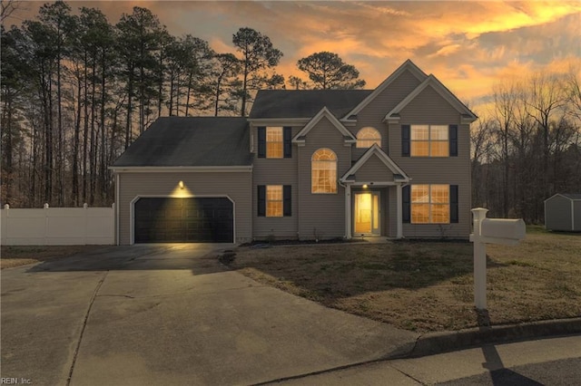 view of front of house featuring an attached garage, a storage shed, fence, driveway, and a front yard