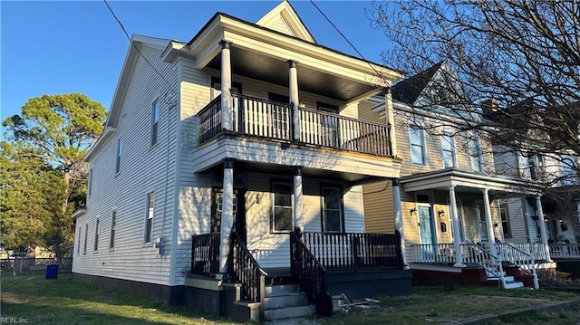 view of front of house featuring covered porch, a balcony, and a front lawn