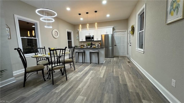 kitchen with baseboards, dark countertops, wood finished floors, stainless steel appliances, and white cabinetry