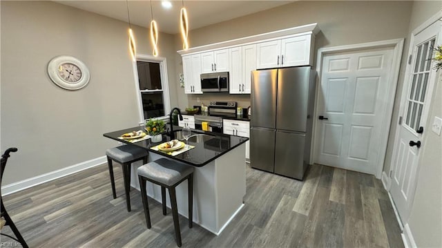 kitchen with a sink, white cabinetry, a kitchen breakfast bar, appliances with stainless steel finishes, and a center island with sink