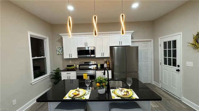 kitchen featuring stainless steel appliances, dark countertops, a kitchen bar, and white cabinets