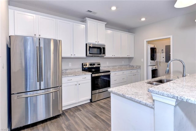 kitchen featuring stacked washer and dryer, white cabinetry, appliances with stainless steel finishes, and a sink