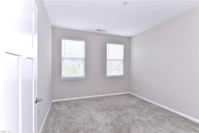 empty room featuring baseboards, visible vents, and light colored carpet