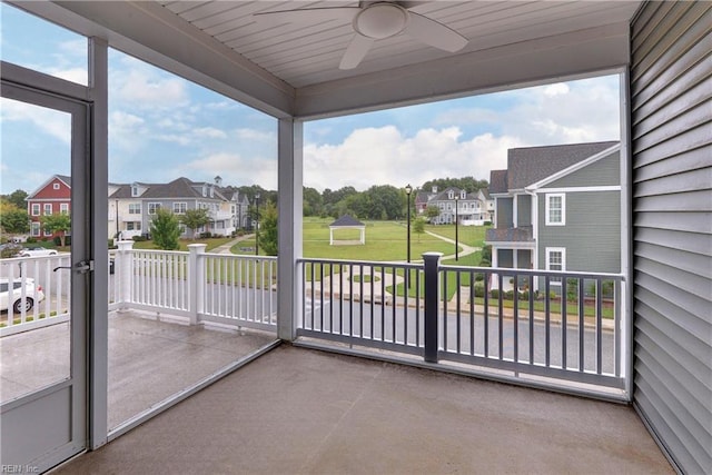 sunroom / solarium featuring ceiling fan and a residential view