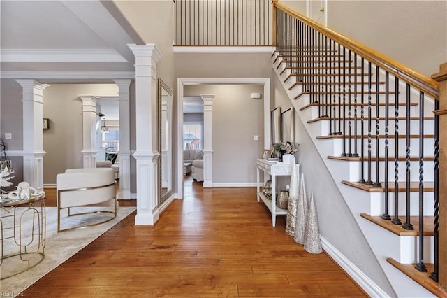 entrance foyer with baseboards, stairs, hardwood / wood-style floors, decorative columns, and crown molding