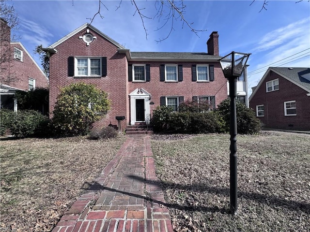 view of front of house featuring a chimney and brick siding