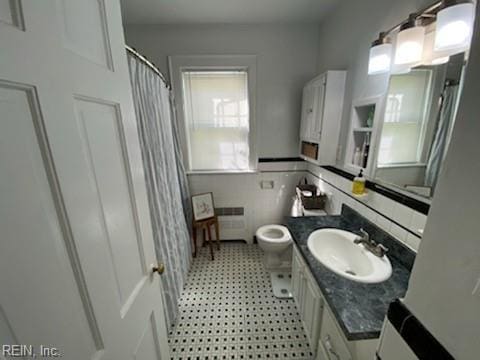 bathroom featuring tile walls, radiator, toilet, wainscoting, and vanity