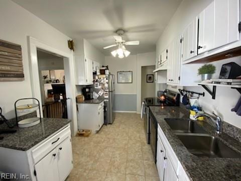 kitchen featuring electric range oven, white cabinetry, a sink, ceiling fan, and dark stone counters