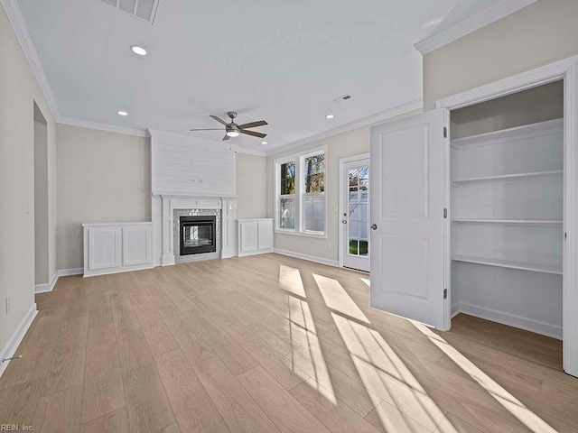 unfurnished living room with a glass covered fireplace, crown molding, light wood-style flooring, and baseboards