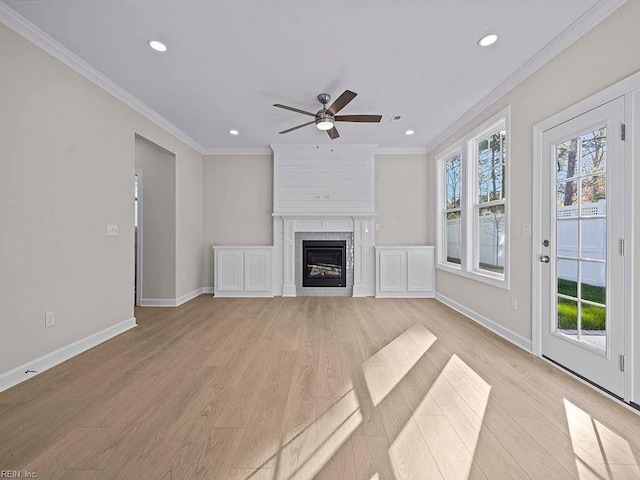 unfurnished living room featuring crown molding, a fireplace, light wood-style flooring, and a healthy amount of sunlight