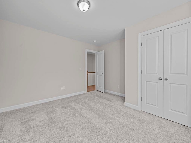 unfurnished bedroom with light carpet, a closet, and baseboards