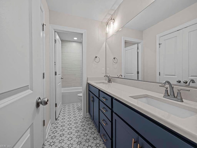 bathroom featuring toilet, double vanity, shower / washtub combination, and a sink