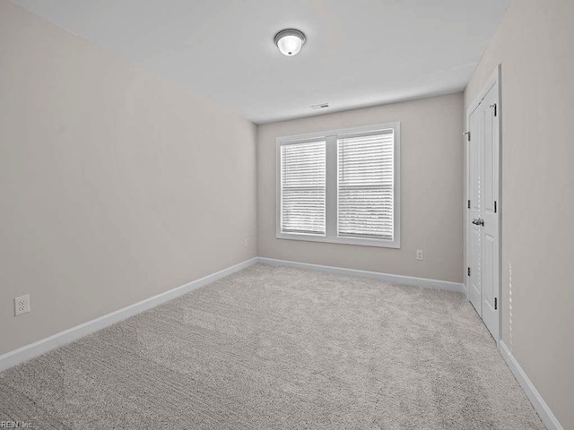 empty room with light carpet, visible vents, and baseboards