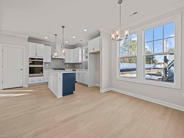 kitchen featuring pendant lighting, light countertops, a kitchen island, and white cabinetry