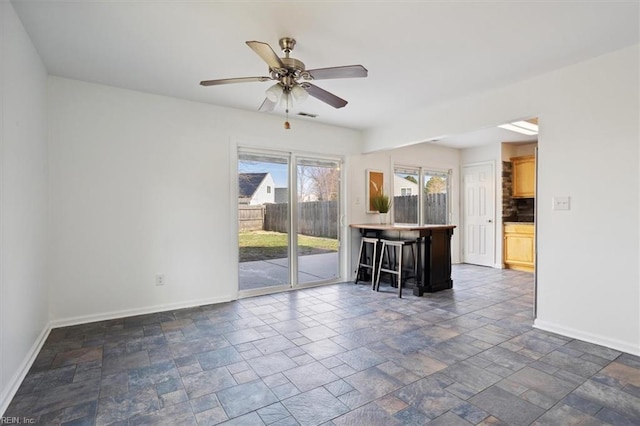 interior space with stone finish flooring, ceiling fan, and baseboards