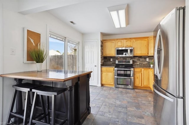 kitchen featuring stainless steel appliances, tasteful backsplash, visible vents, and light brown cabinetry