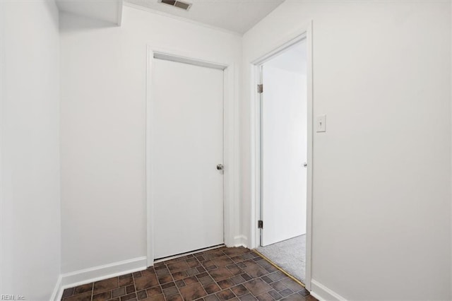 hall featuring stone finish floor, visible vents, and baseboards