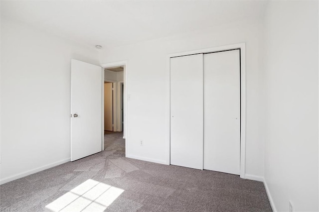 unfurnished bedroom featuring light carpet, a closet, and baseboards