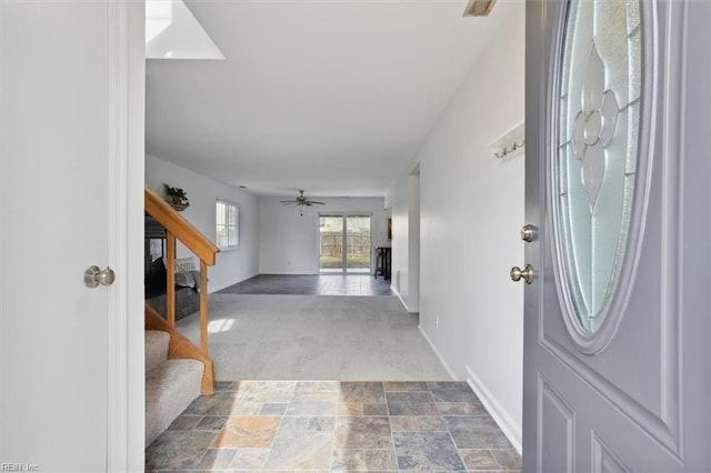 foyer with stone finish floor, ceiling fan, baseboards, and stairs