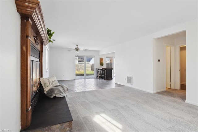 unfurnished living room featuring a ceiling fan, carpet, visible vents, and baseboards