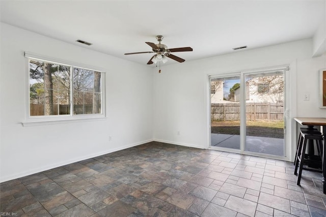 empty room featuring stone finish floor, visible vents, and baseboards