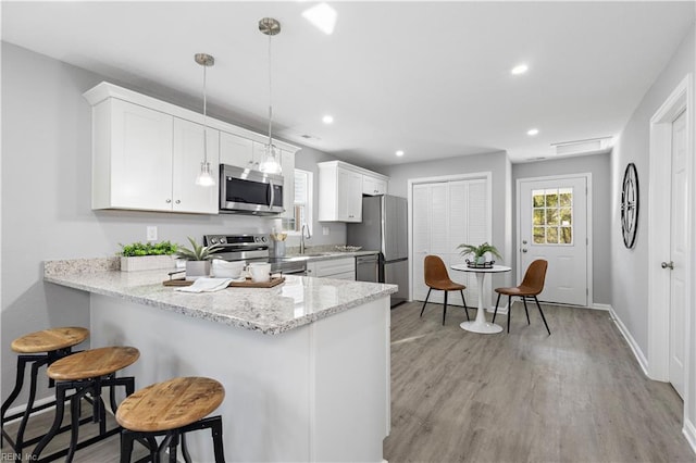 kitchen with a breakfast bar area, recessed lighting, light wood-style flooring, appliances with stainless steel finishes, and baseboards