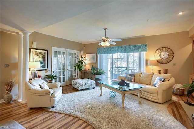 living room featuring decorative columns, ceiling fan, ornamental molding, wood finished floors, and french doors