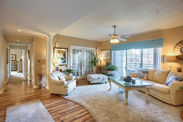 living room featuring wood finished floors, a ceiling fan, baseboards, french doors, and ornate columns