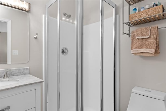 bathroom featuring vanity, a shower stall, and toilet