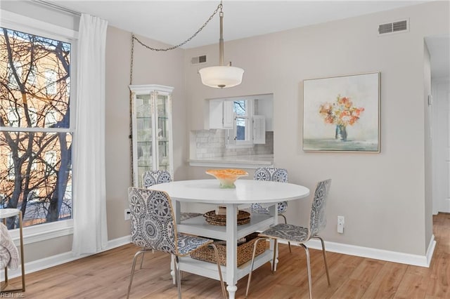 dining room with light wood-style floors, baseboards, visible vents, and breakfast area