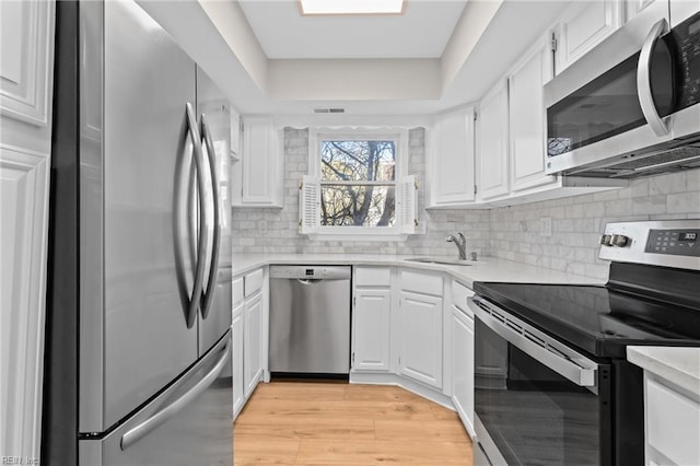 kitchen with a sink, stainless steel appliances, light countertops, and white cabinets